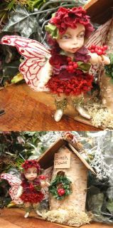hanging her holly wreath on the front of her little birch house